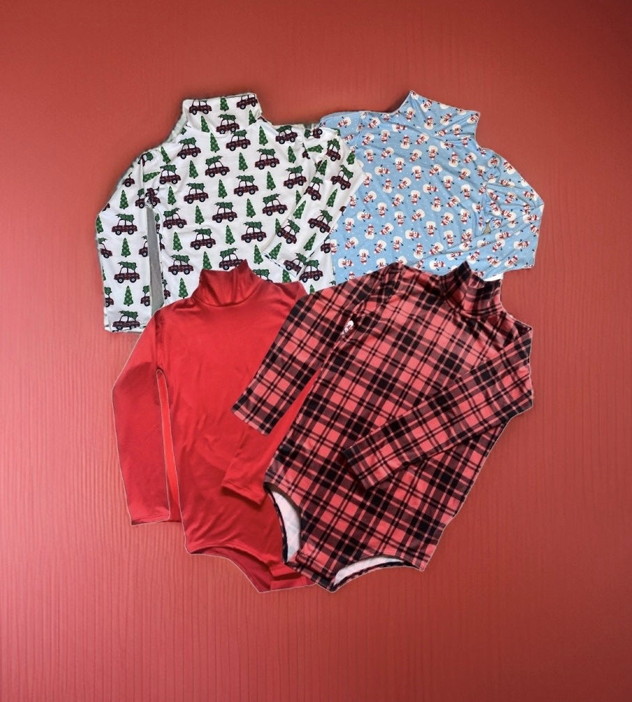 Colorful pile of children's clothing on red surface, showcasing unisex onesies