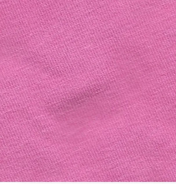 A close-up of a pink shirt with a small white patch.
