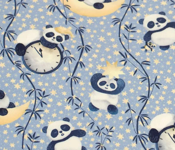 Panda bears sitting under a crescent moon on a blue fabric